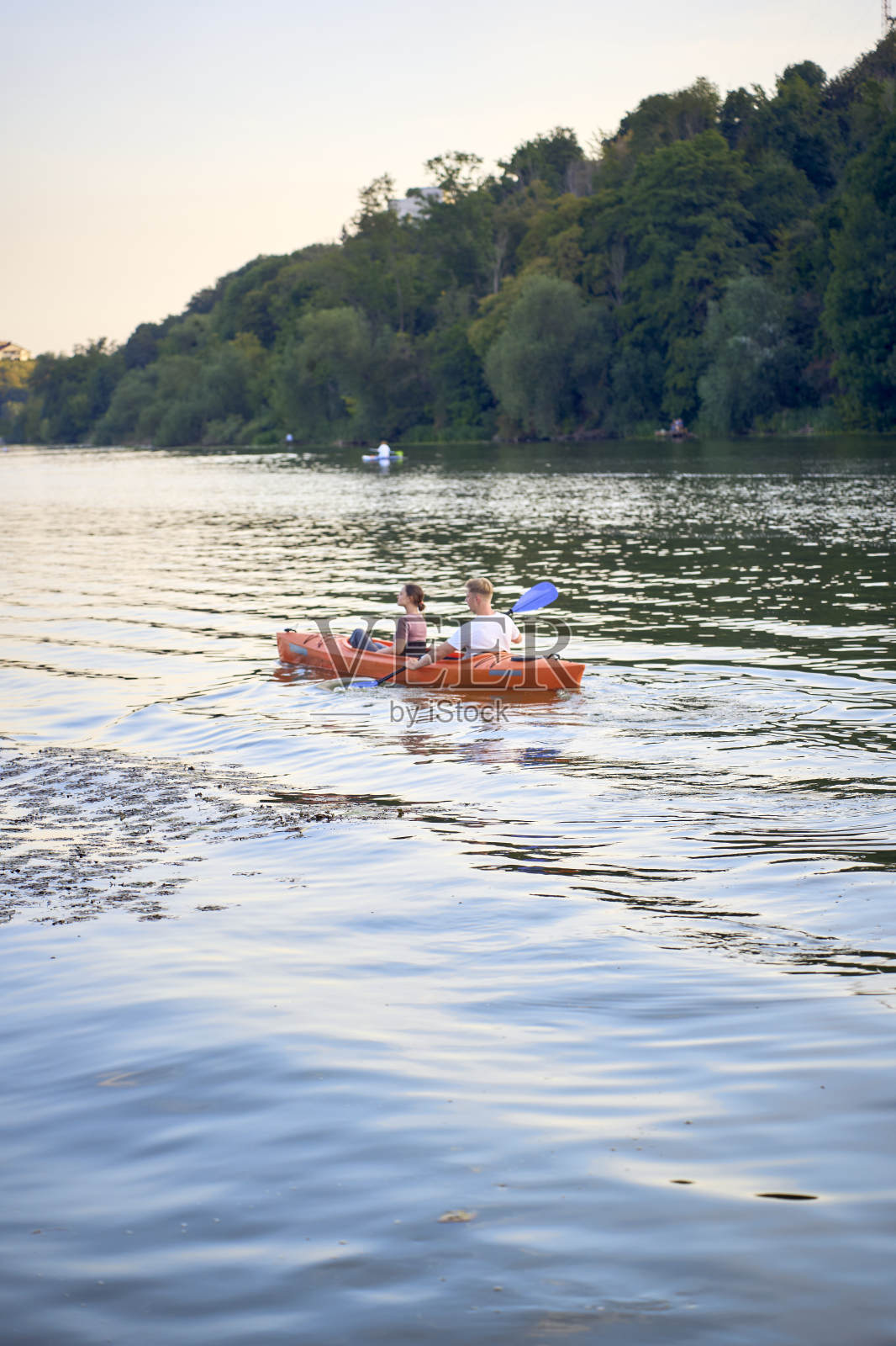 那对相爱的夫妇在日落时分在河上划皮艇照片摄影图片