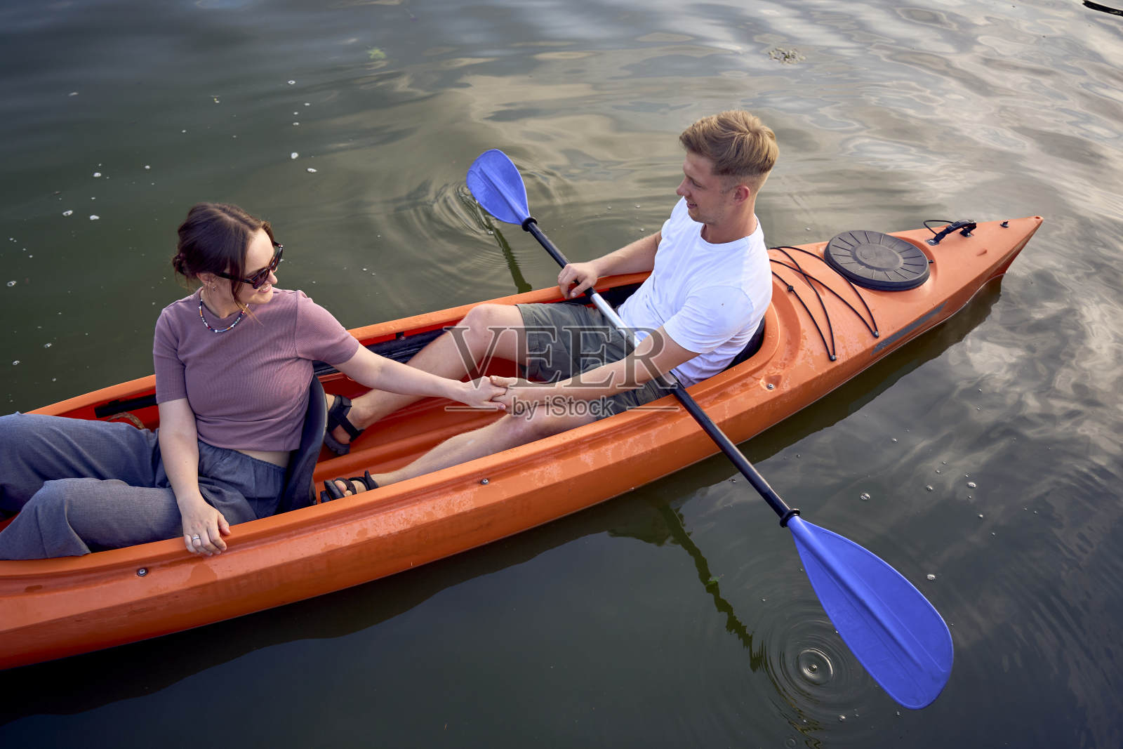 那对相爱的夫妇在日落时分在河上划皮艇照片摄影图片