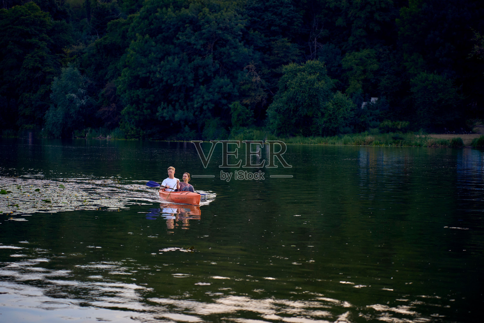 那对相爱的夫妇在日落时分在河上划皮艇照片摄影图片