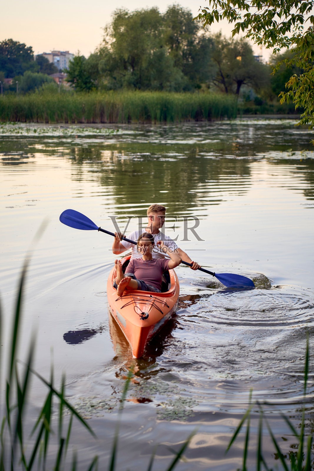 那对相爱的夫妇在日落时分在河上划皮艇照片摄影图片