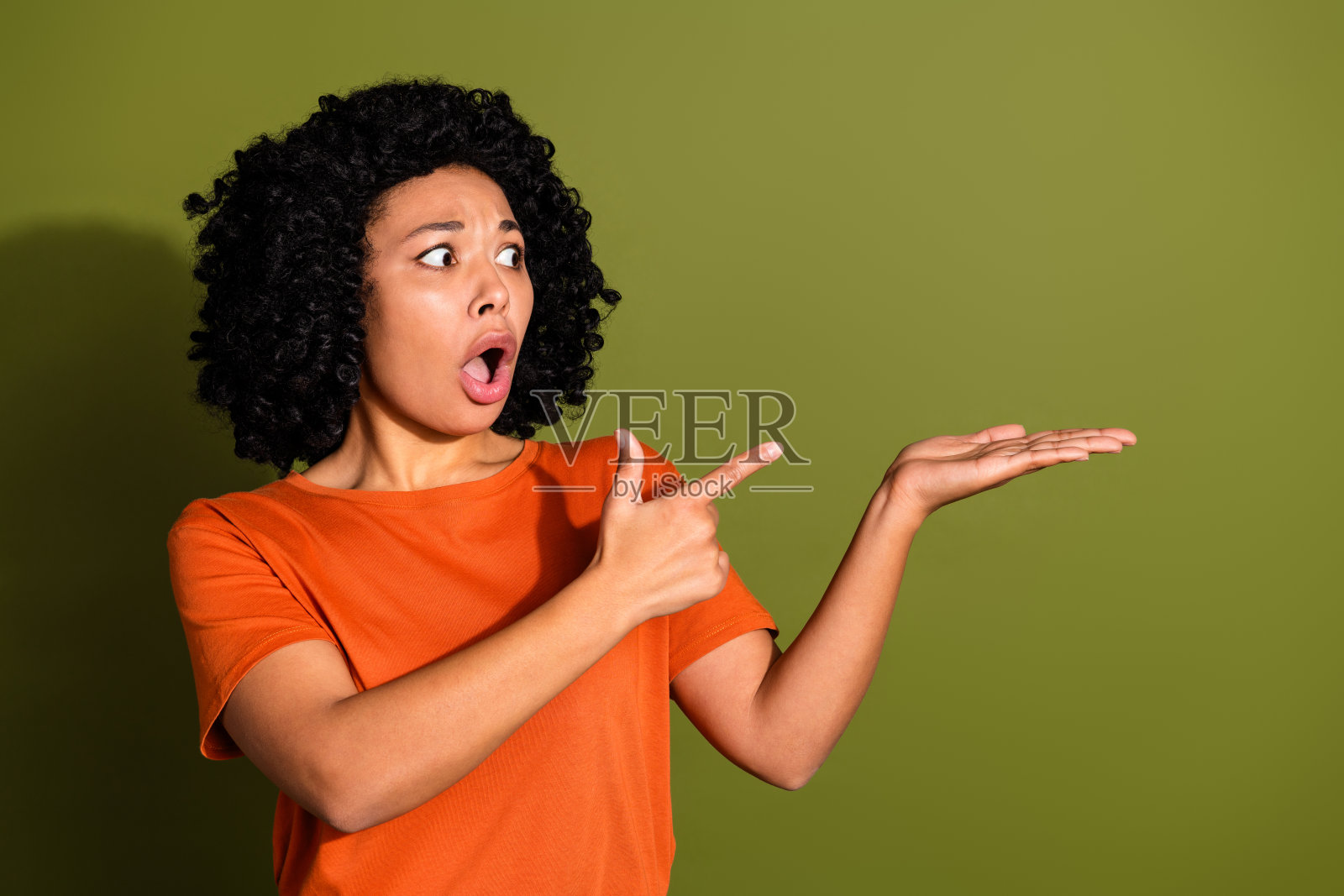 漂亮的年轻女孩的照片肖像点握着害怕的目光空空穿着时髦的橙色服装孤立在卡其色的背景照片摄影图片