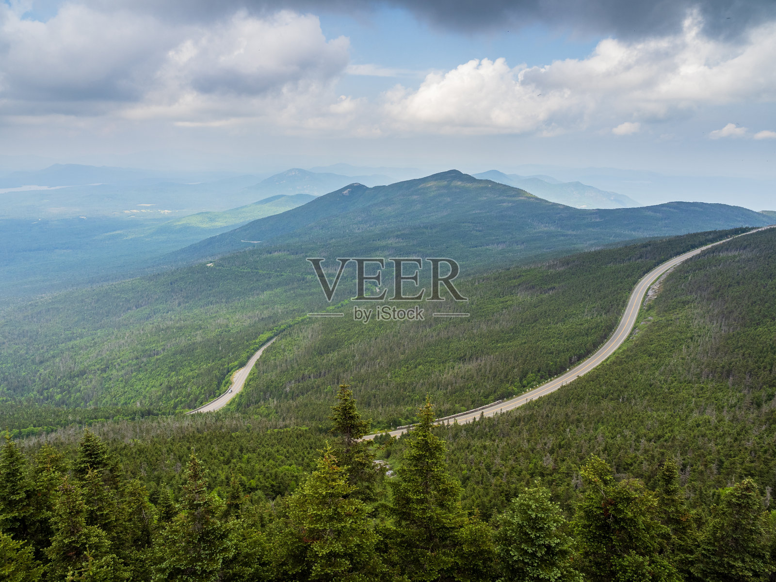 从纽约州北部普莱西德湖外的威尔明顿的怀特法斯山上看到蜿蜒的纪念公路，背景是山脉。照片摄影图片