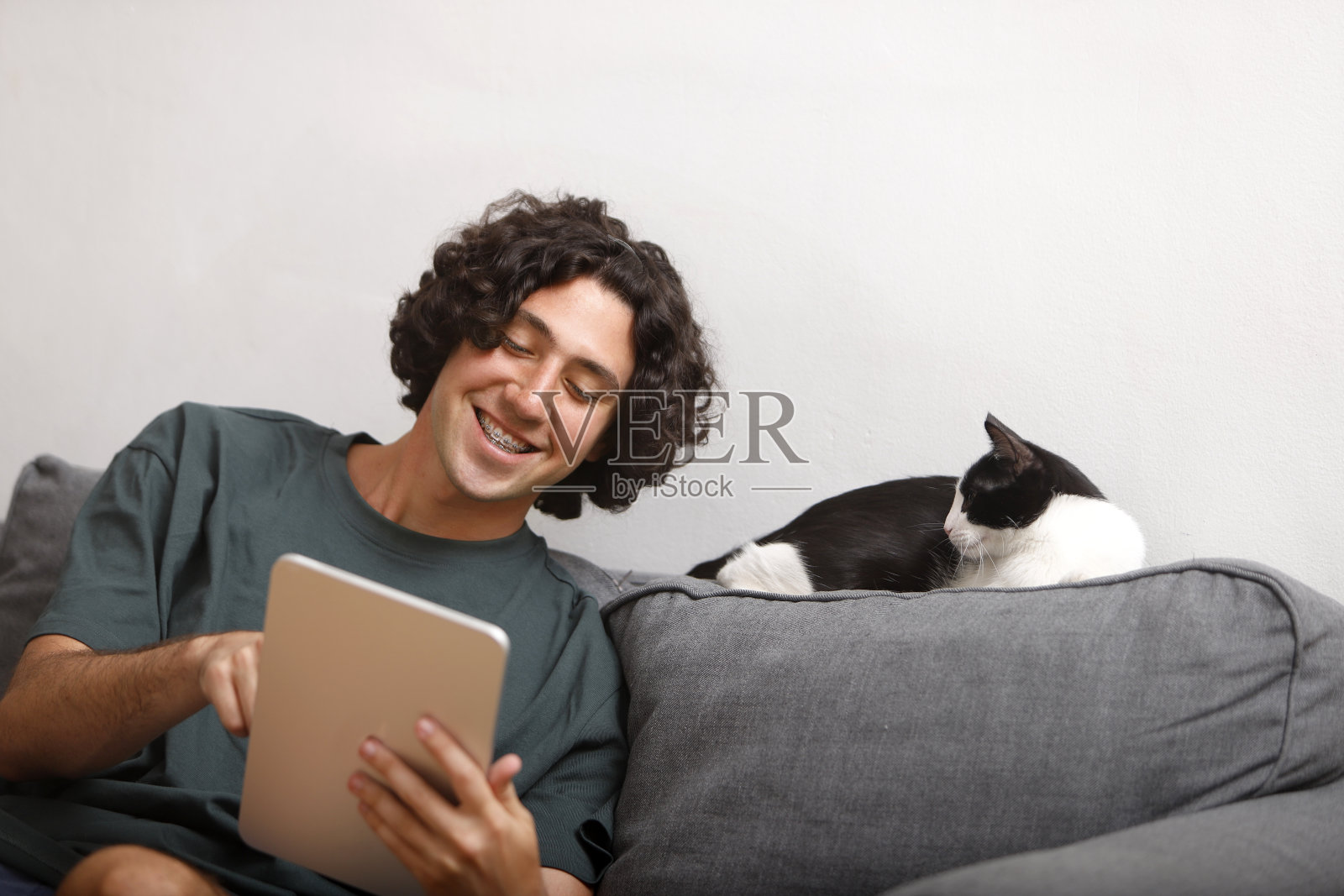 拿着平板电脑的小男孩给他的猫看东西照片摄影图片