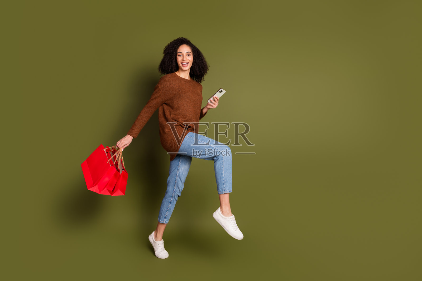 完整的肖像漂亮的年轻女子电话商场袋穿毛衣孤立的卡其色背景照片摄影图片