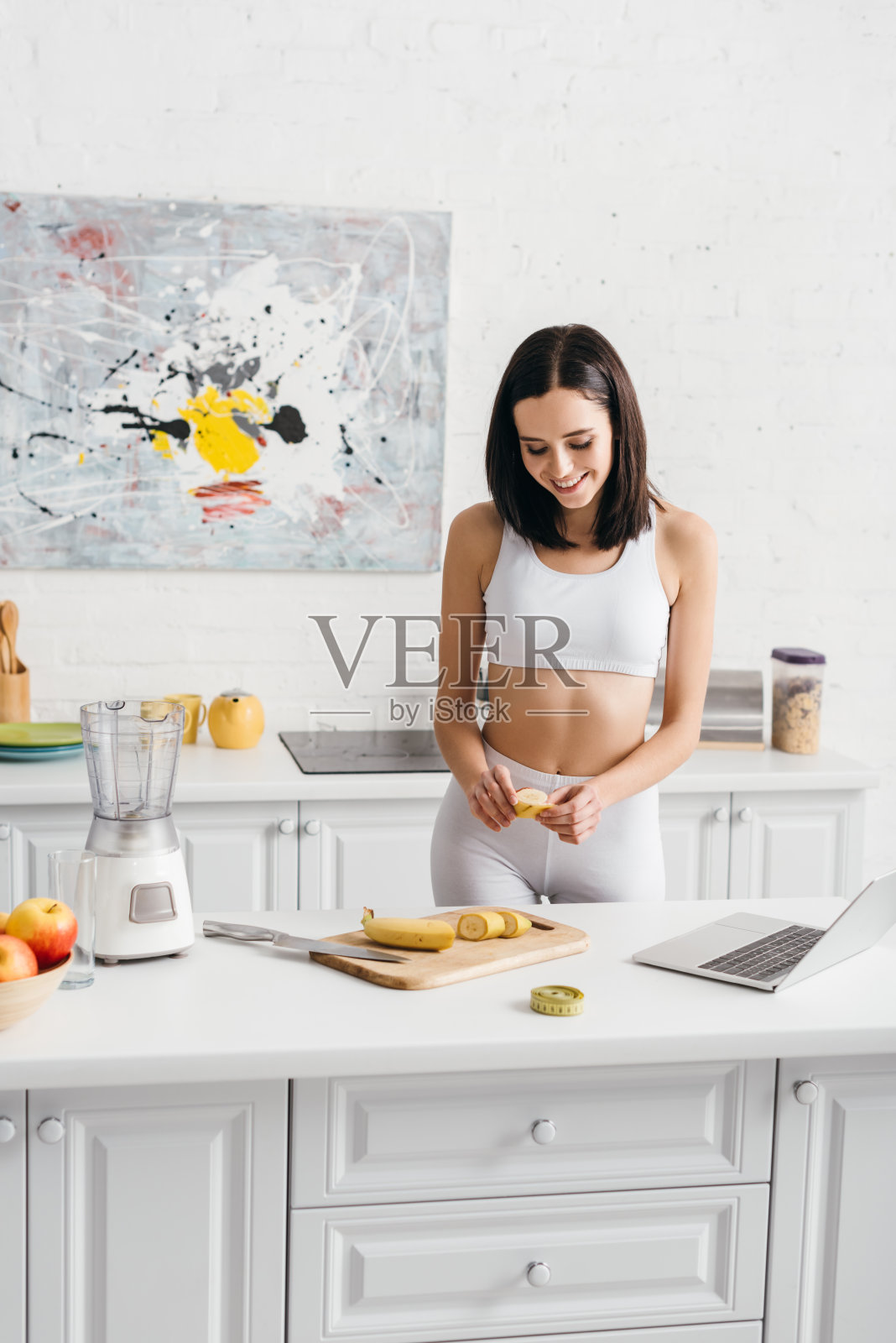 穿着运动服的年轻女子在家里时髦的现代厨房里调制冰沙照片摄影图片