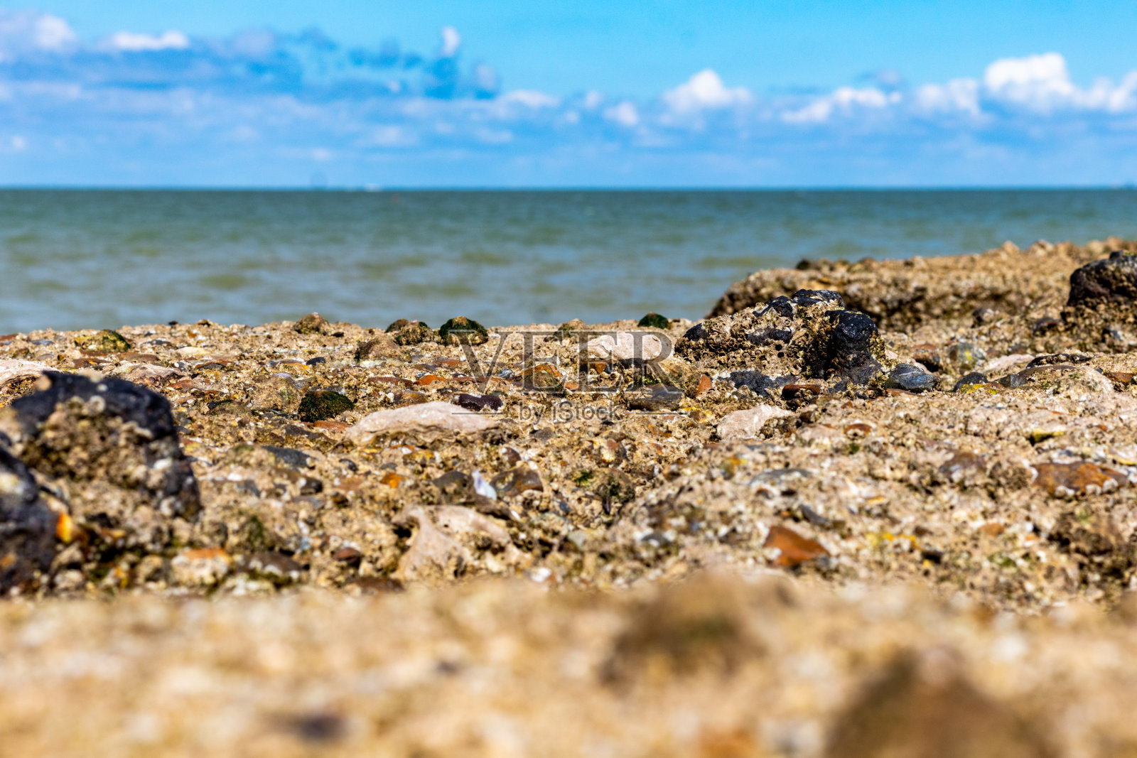 英国马盖特的岩石海岸，背景是模糊的海洋和天空。照片摄影图片