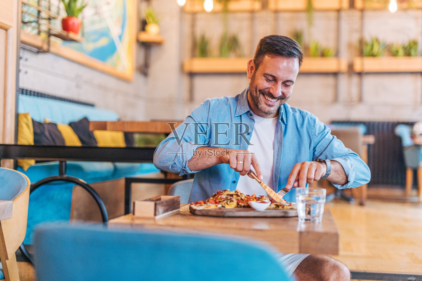 快乐英俊的中年男人在餐厅吃披萨照片摄影图片