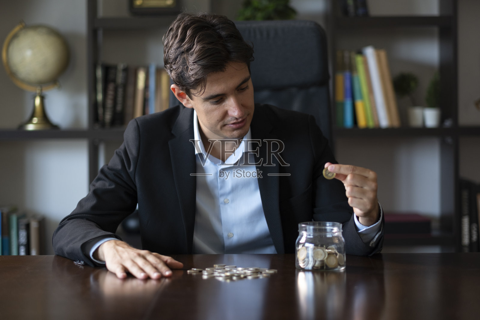 西装商人把钱放进罐子里存起来。理财理念，理财账户，商业投资。财务规划照片摄影图片