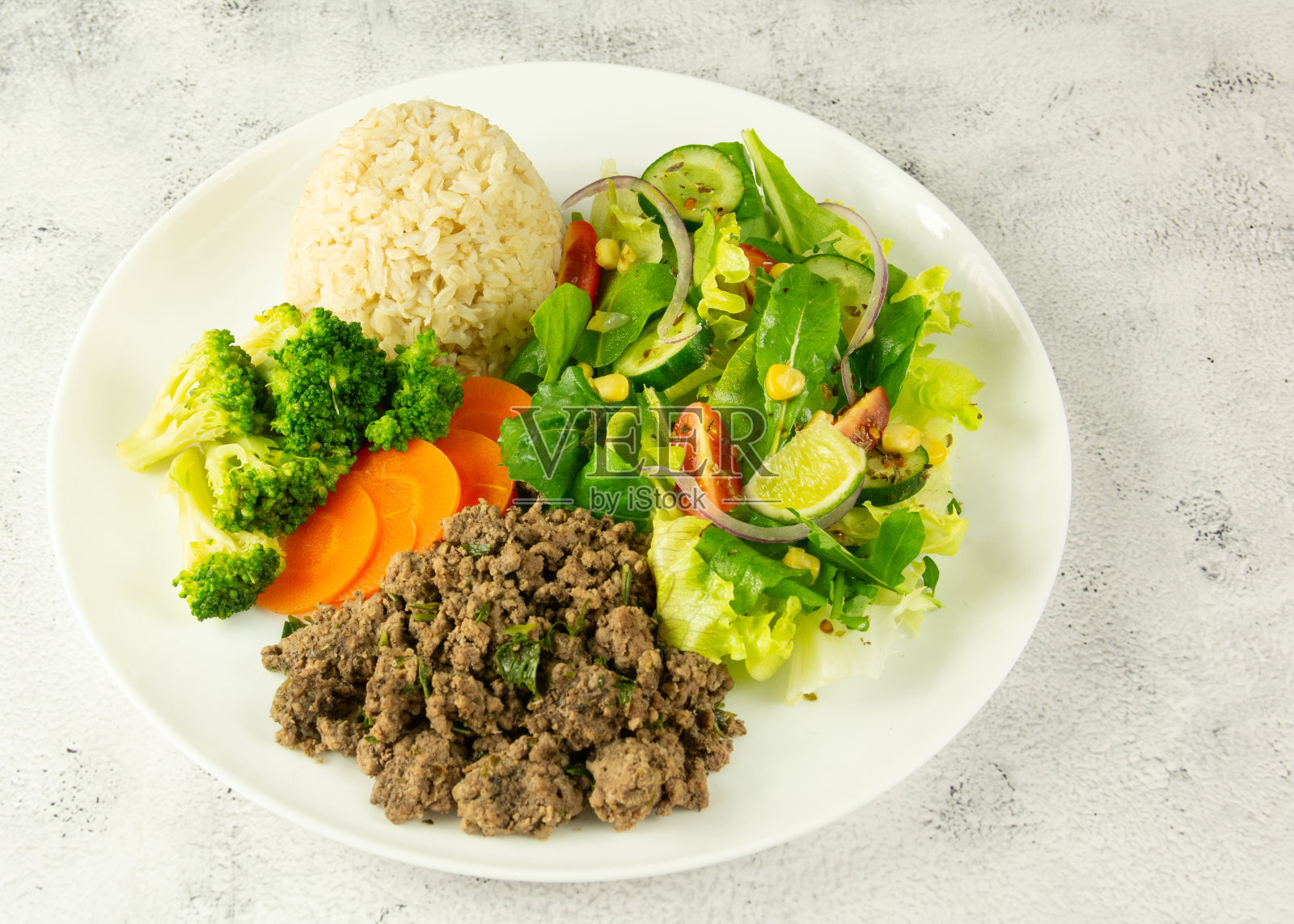 美味的碎牛肉配蒸西兰花，胡萝卜，糙米，和充满活力的混合蔬菜沙拉。照片摄影图片