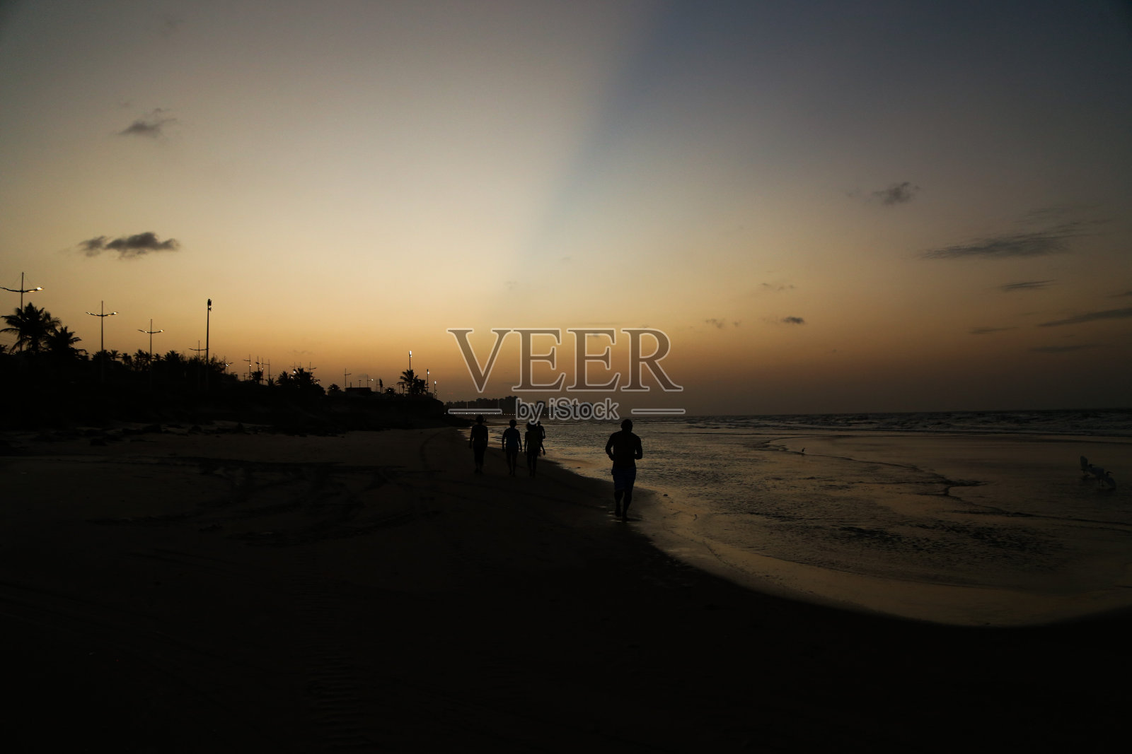 日落时分在沙滩上奔跑的人照片摄影图片