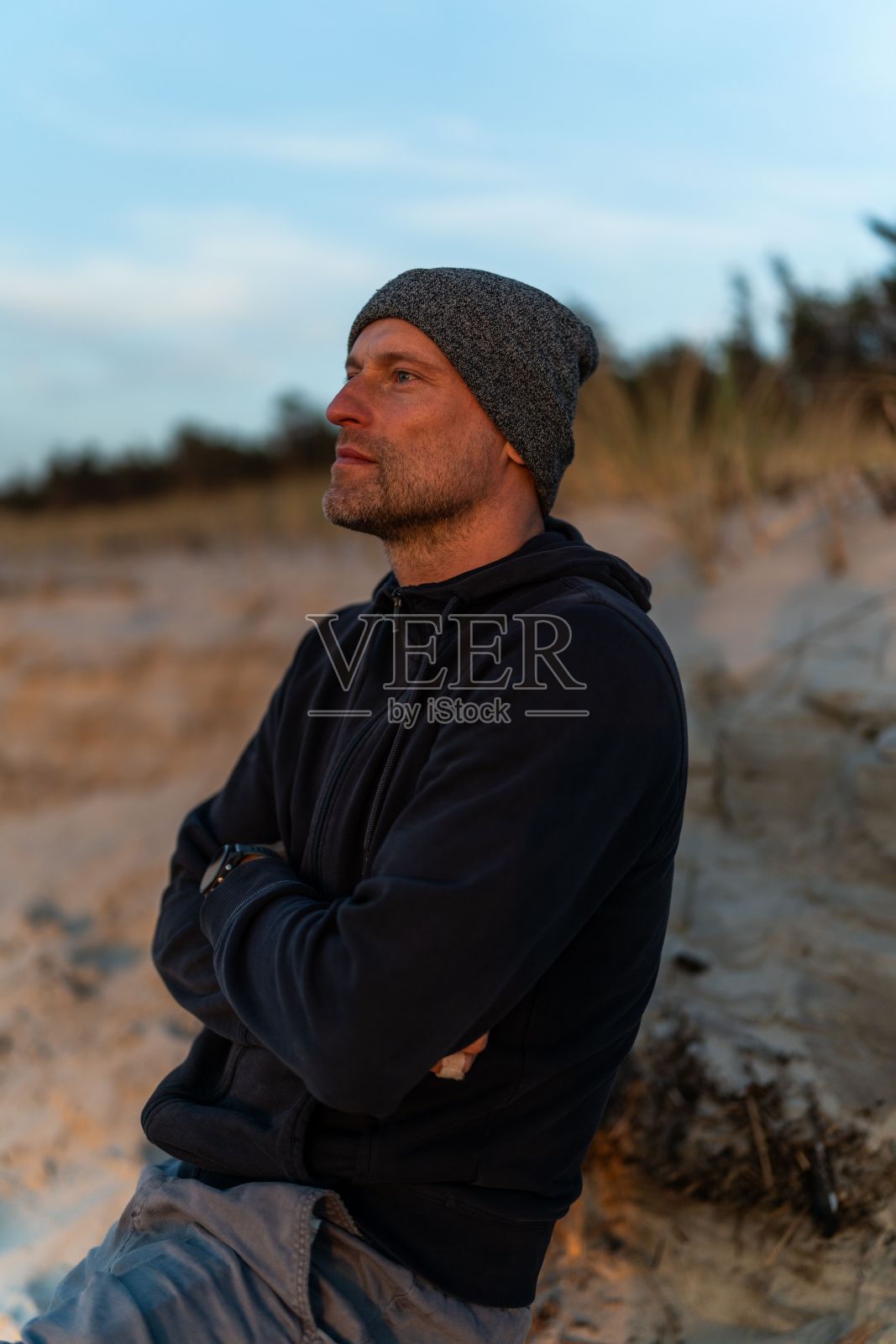 一名身着休闲服的男子坐在夕阳下的波兰沙滩上照片摄影图片