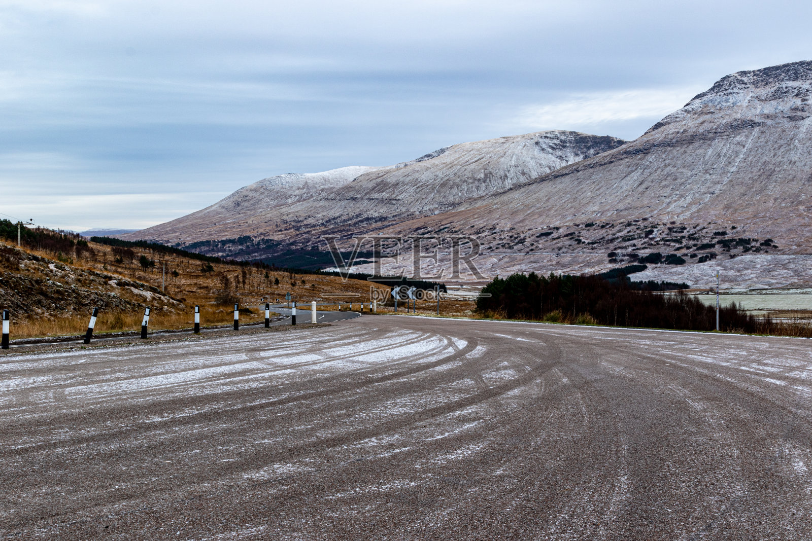 蜿蜒的道路在雪峰和多云的天空的山区景观。照片摄影图片