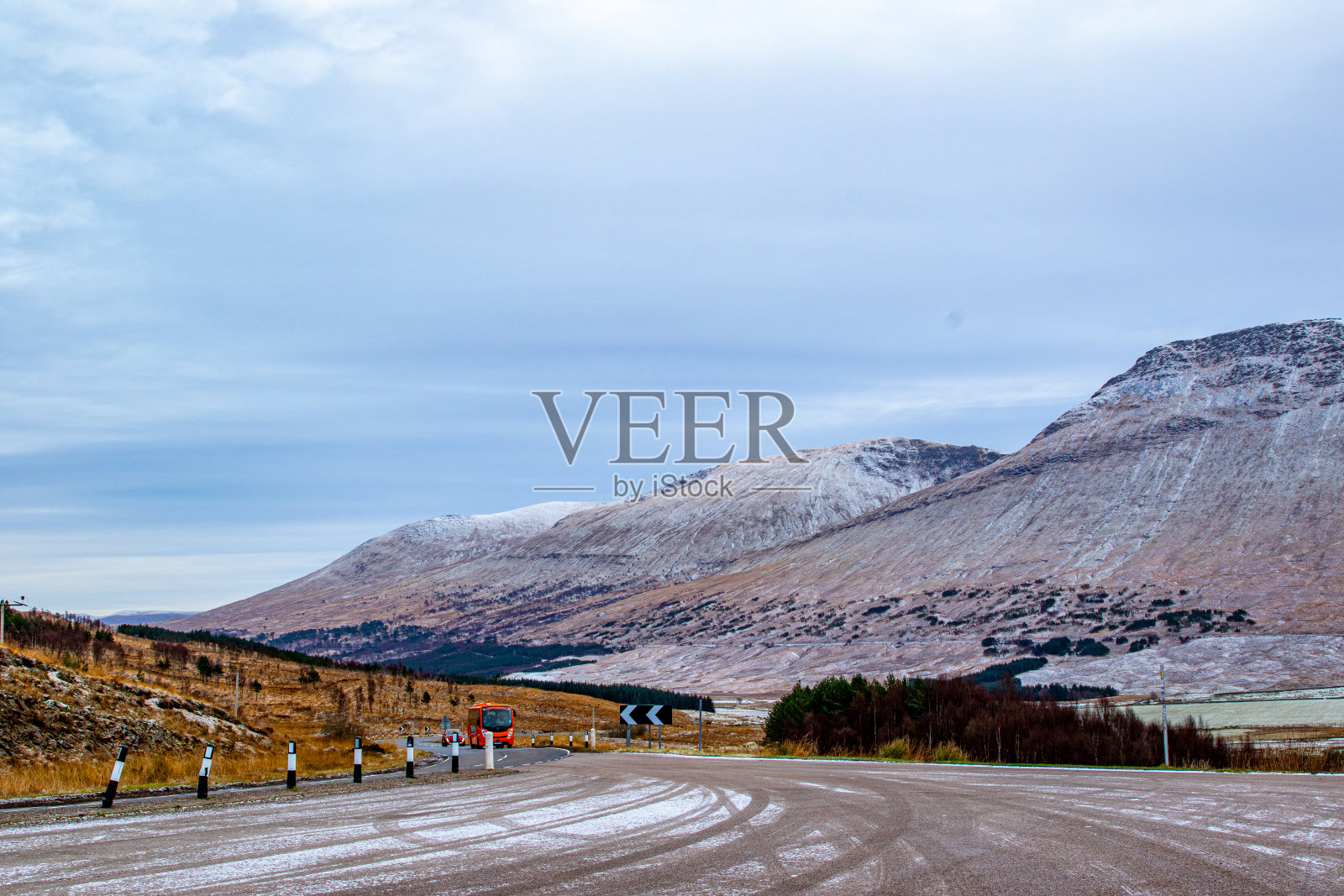 在多云的天空下，空旷的道路通向风景秀丽的雪峰。照片摄影图片