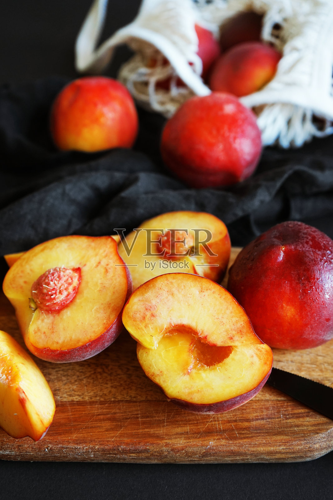 成熟的切好的桃子放在木板上，一张亚麻布餐巾，旁边是刀和绳袋照片摄影图片