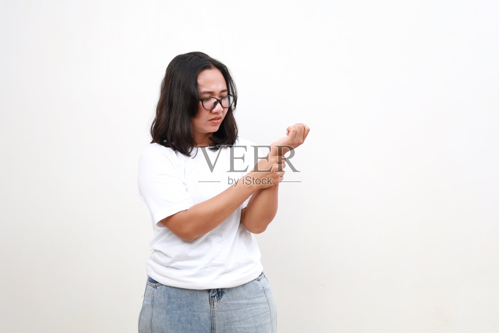 年轻的亚洲女性按摩手遭受关节疼痛。患有风湿性关节炎的女孩。女人摸着手腕感到疼痛。骨关节炎是老年疾病的概念。照片摄影图片