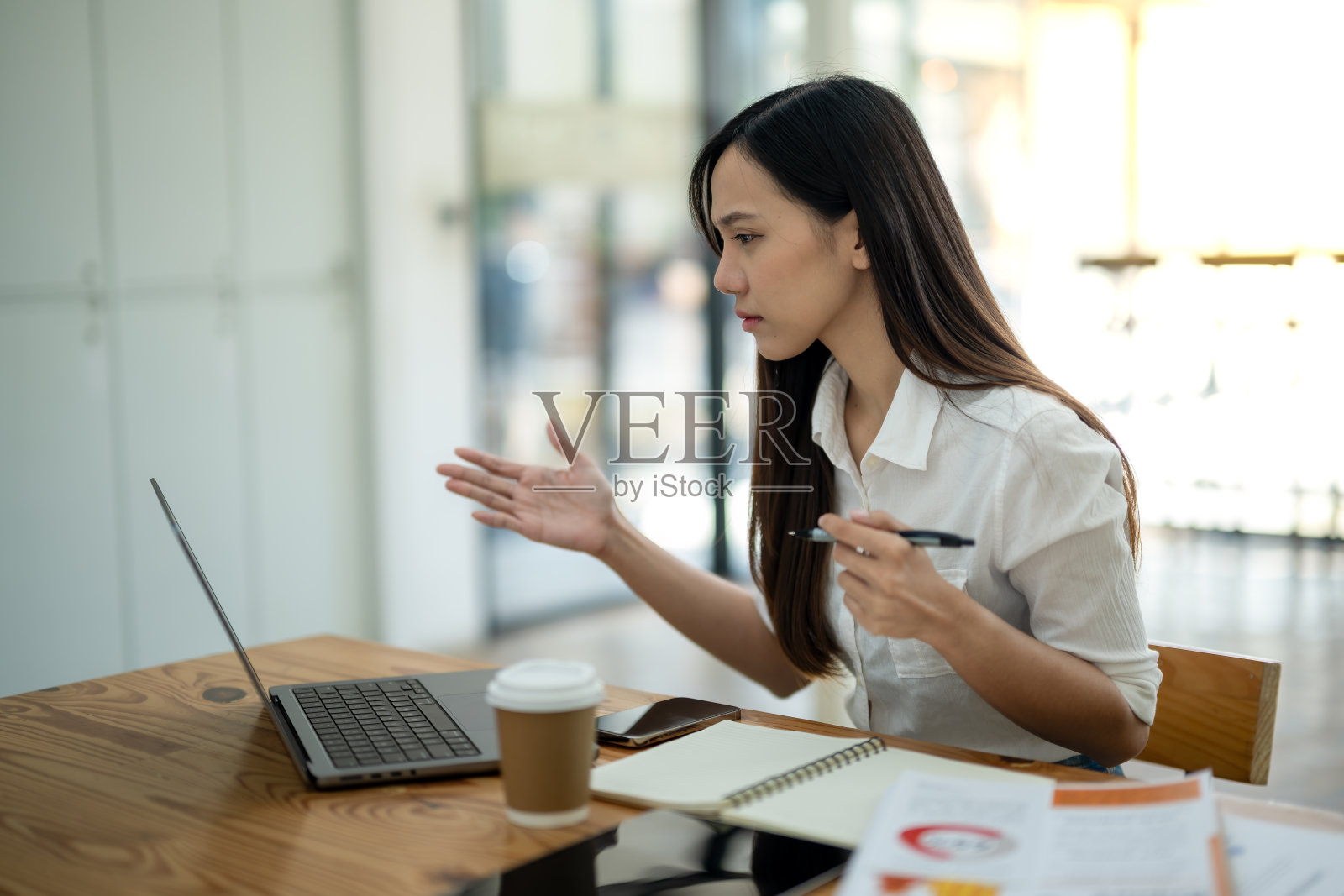 在办公室的视频会议上，一名忙碌的亚洲女商人在用笔记本电脑解释一个概念。照片摄影图片