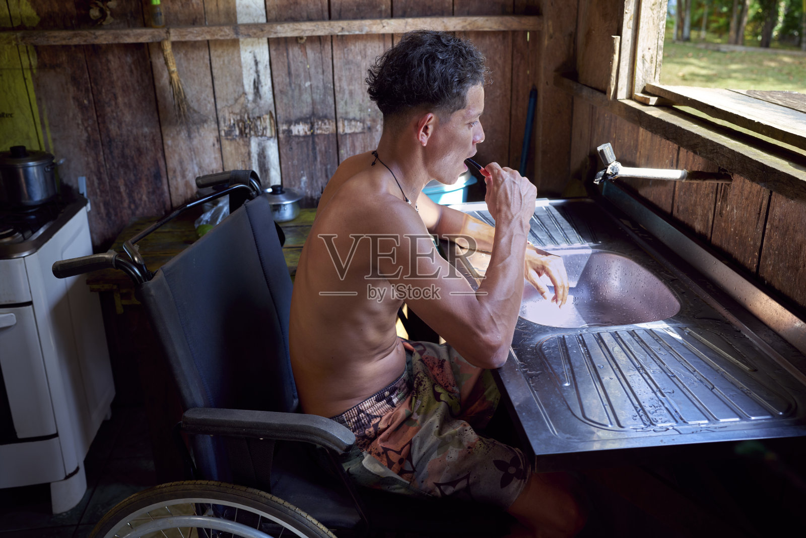 一个来自巴西亚马逊地区的残疾土著小男孩坐在轮椅上，在水槽里洗牙照片摄影图片