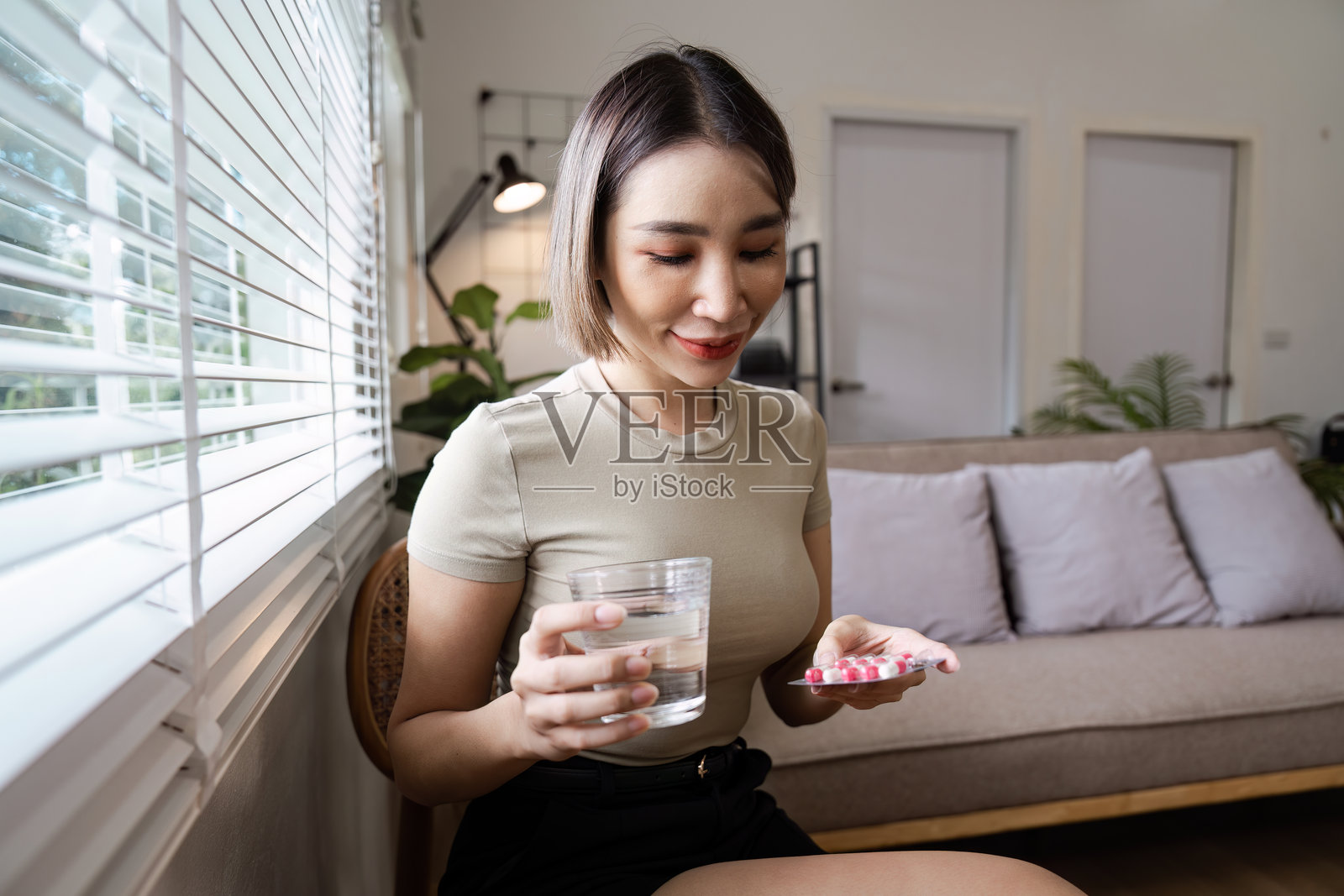 年轻女子在现代客厅用水服药，促进健康照片摄影图片