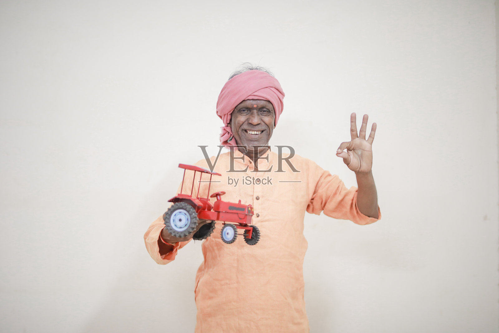 手持微型玩具拖拉机的印度农民照片摄影图片