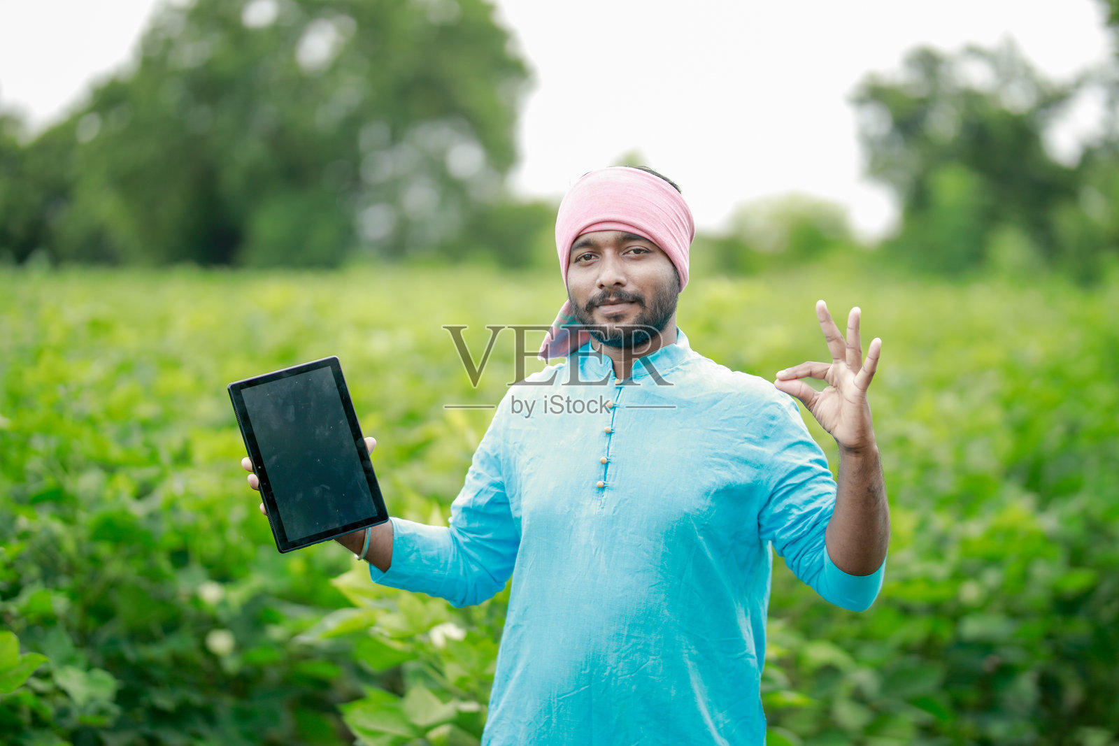 快乐的年轻印度农民使用智能手机照片摄影图片