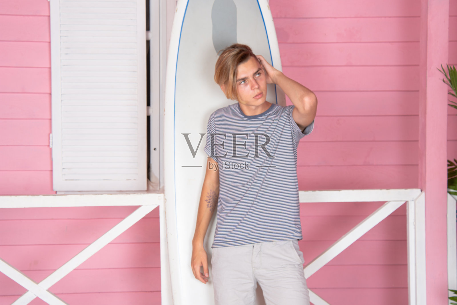 在海上度假。年轻帅气的小伙子在沙滩上拿着冲浪板。照片摄影图片