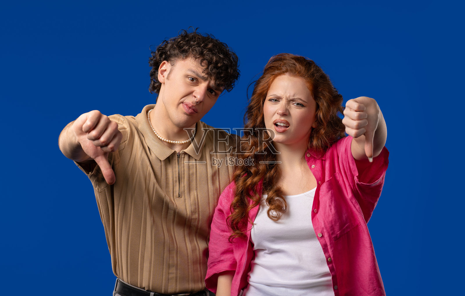 一对不喜欢的年轻夫妇。羞辱男人和女人，大拇指朝下，不喜欢照片摄影图片