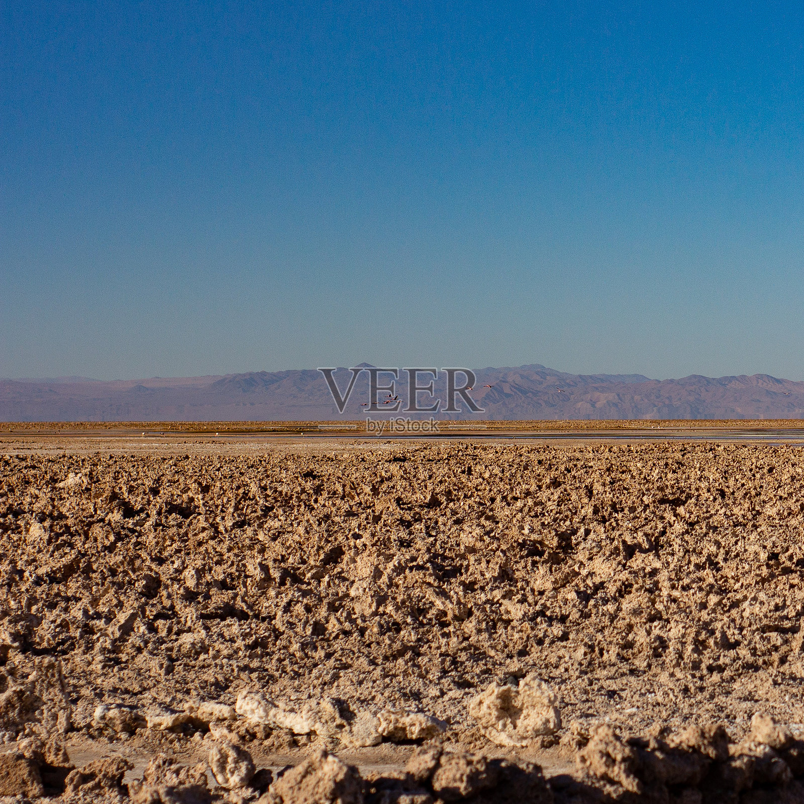 由于沙漠中的水和风侵蚀了土壤，背景中可以看到巨大的山脉照片摄影图片
