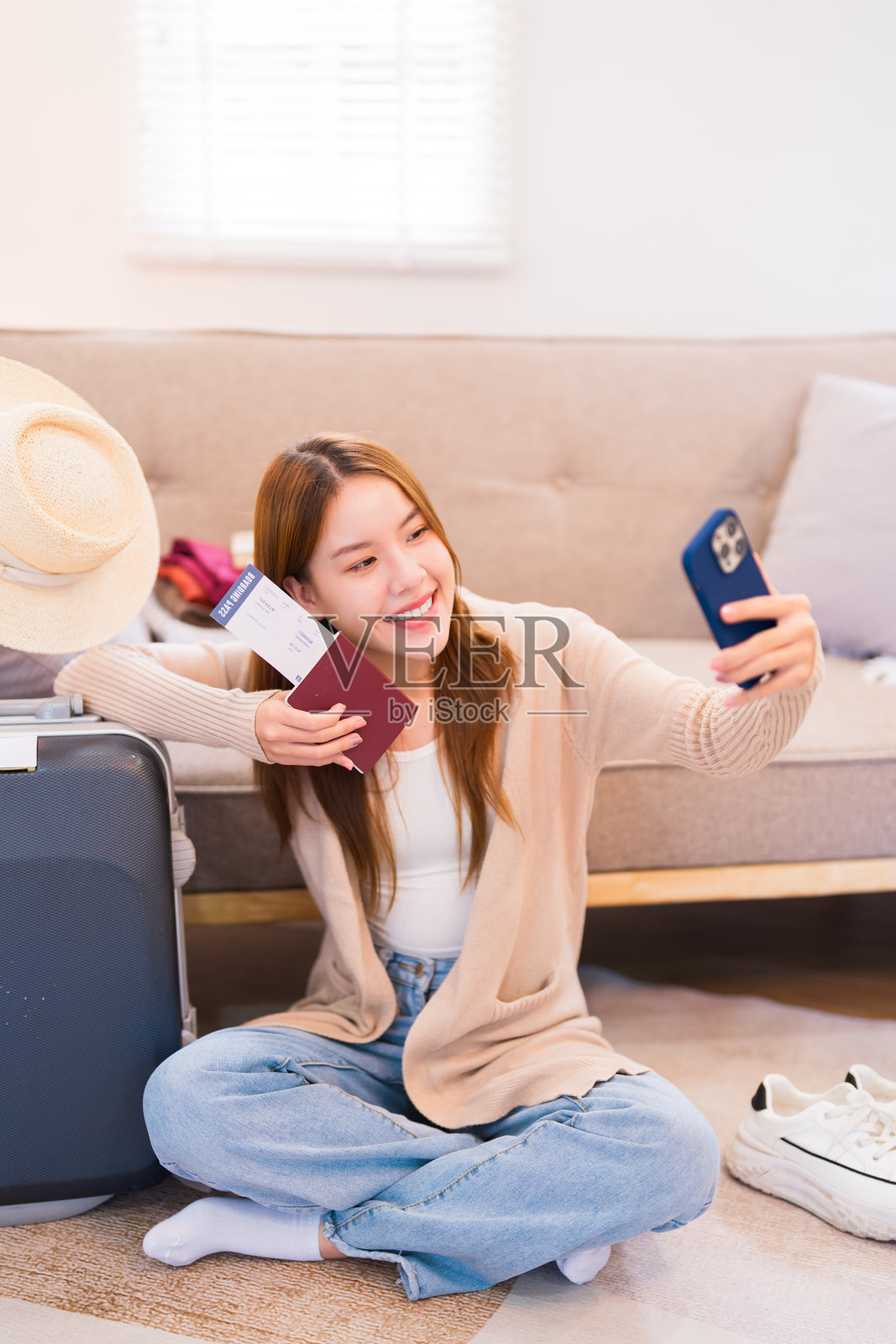 一名年轻女子带着行李自拍，笑容灿烂，为即将到来的旅行做准备，捕捉旅行前的兴奋时刻照片摄影图片