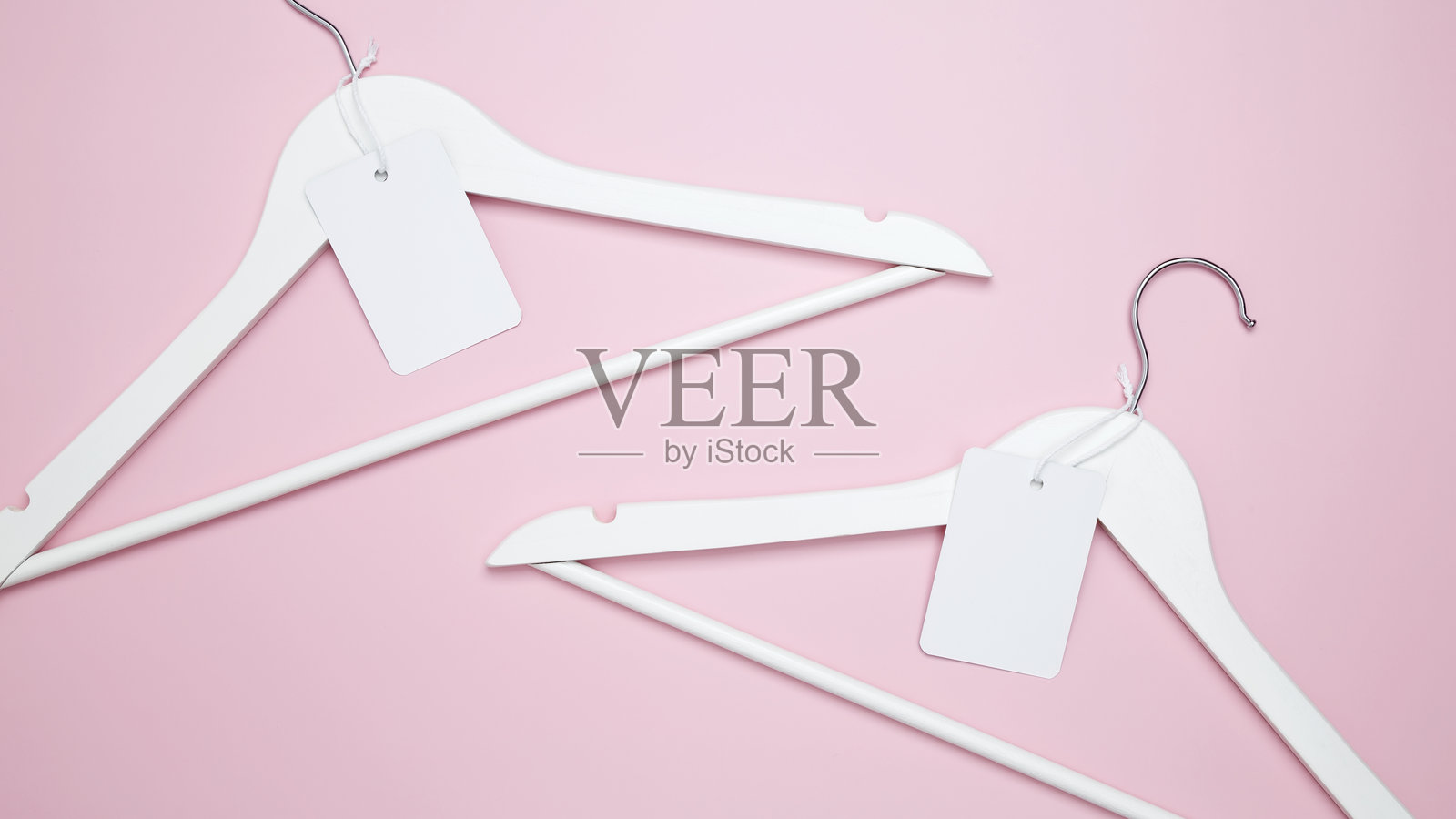 创意平铺衣架与白纸标签。服装吊牌、标签空白样板。打折店促销购物理念。前视图。本空间照片摄影图片