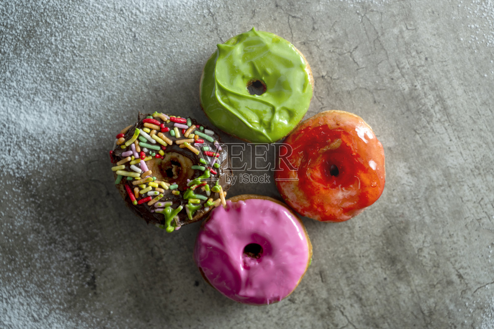 四个不同颜色的迷你甜甜圈，上面撒有糖屑照片摄影图片
