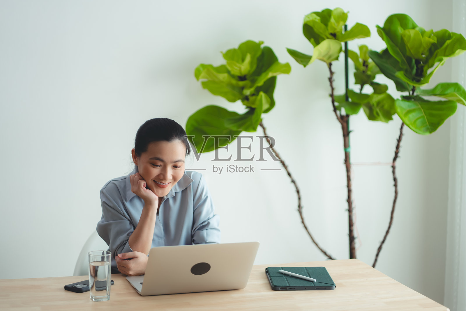 亚洲女性喜欢坐在家里用笔记本电脑上网工作。照片摄影图片