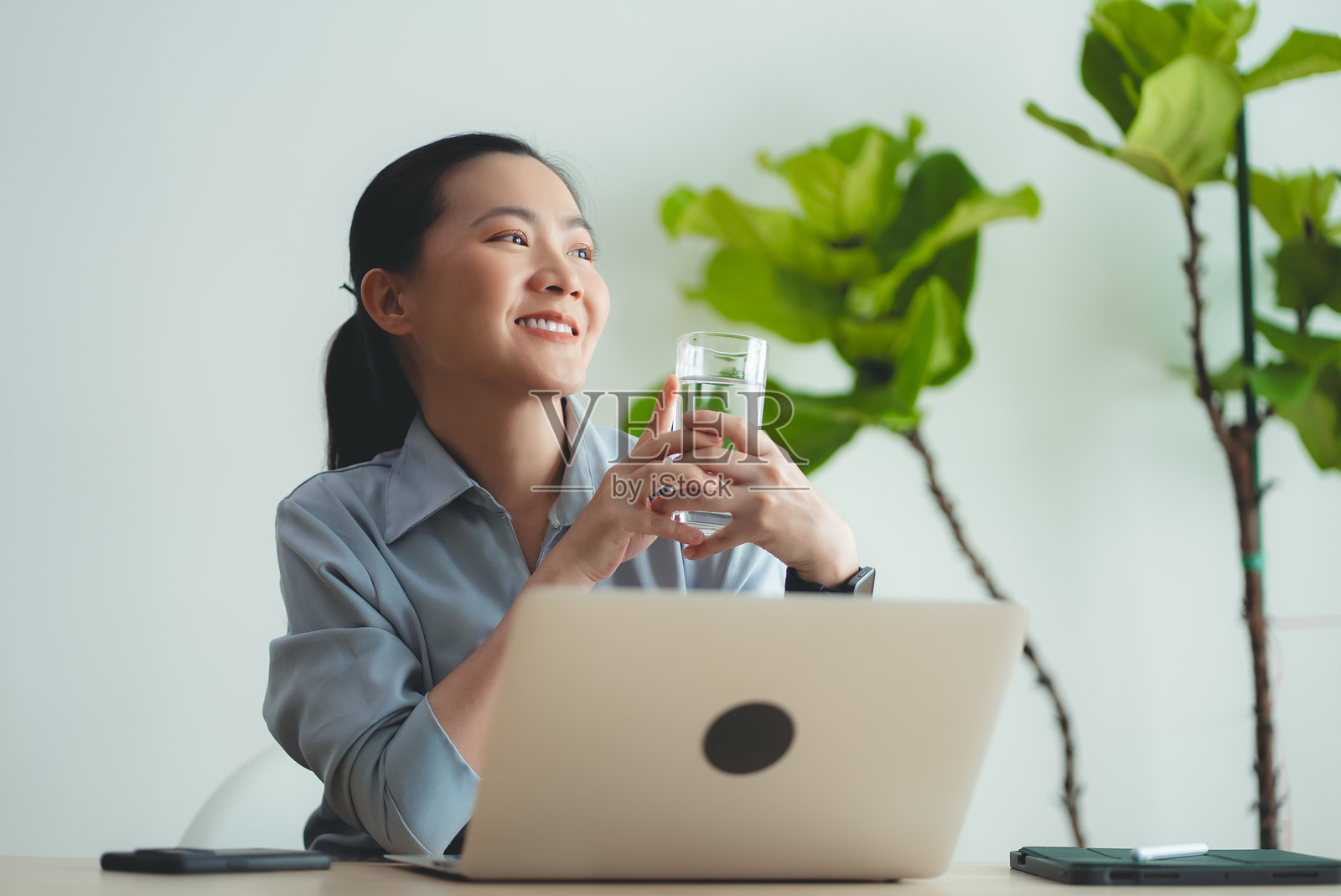 坐在家里办公室喝水休息的亚洲女性。照片摄影图片