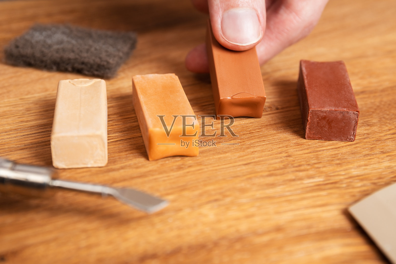 男子配色硬蜡修补裂缝，划痕，凹痕的木地板。专业修补套件，用硬蜡棒强化或镶木地板。家具表面翻新。照片摄影图片