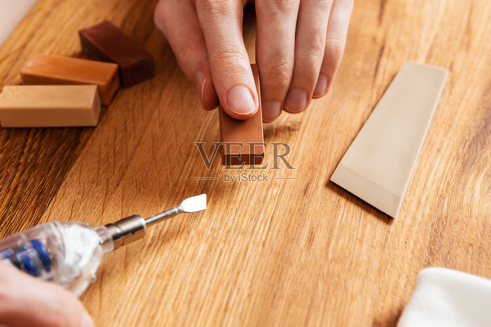 人工加热硬蜡用于修补木地板的裂缝、划痕、凹痕。带有硬蜡棒的专业维修套件。自己动手修复层压板或镶木地板。翻新家具表面。照片摄影图片