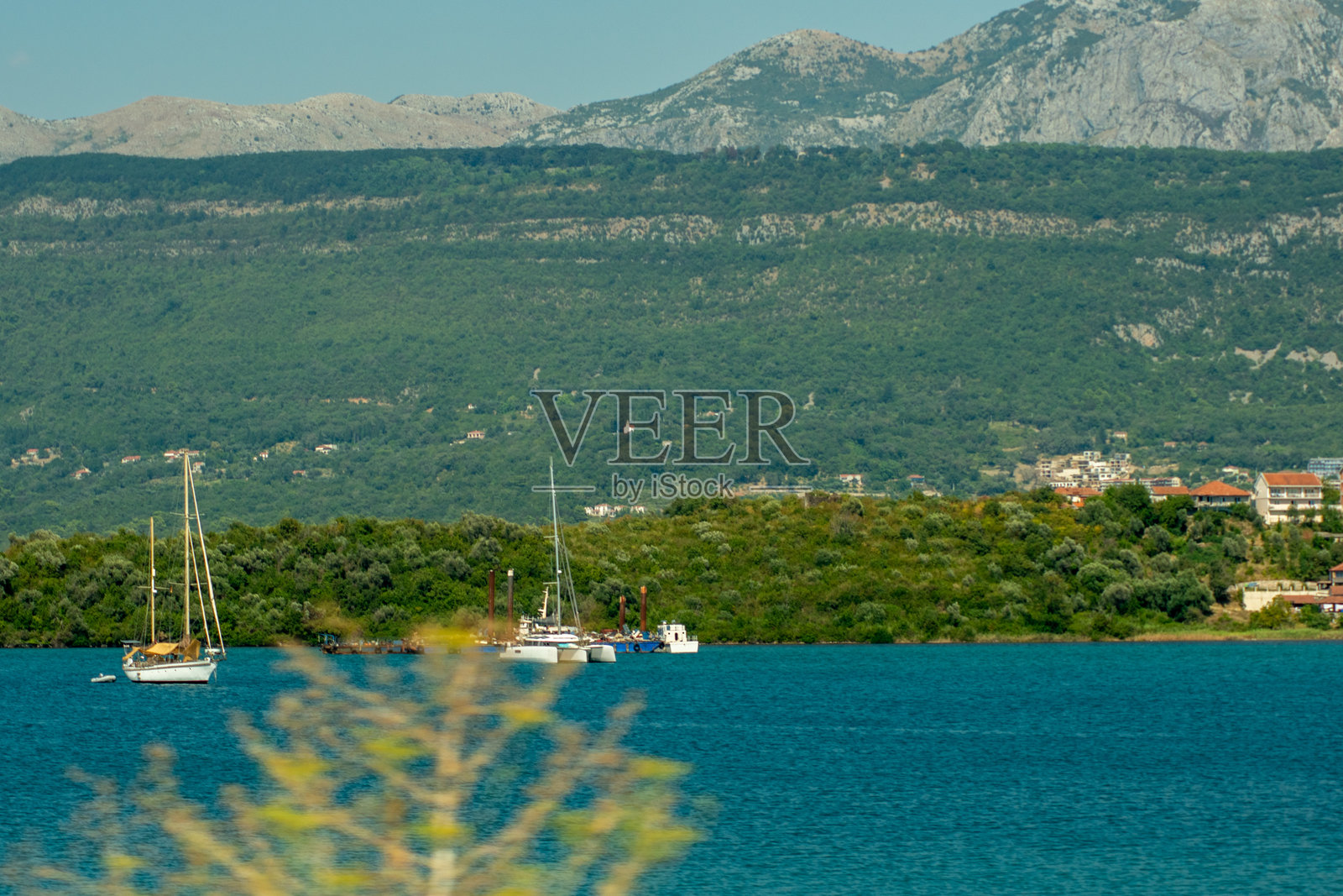 大海上的帆船，背景是群山照片摄影图片