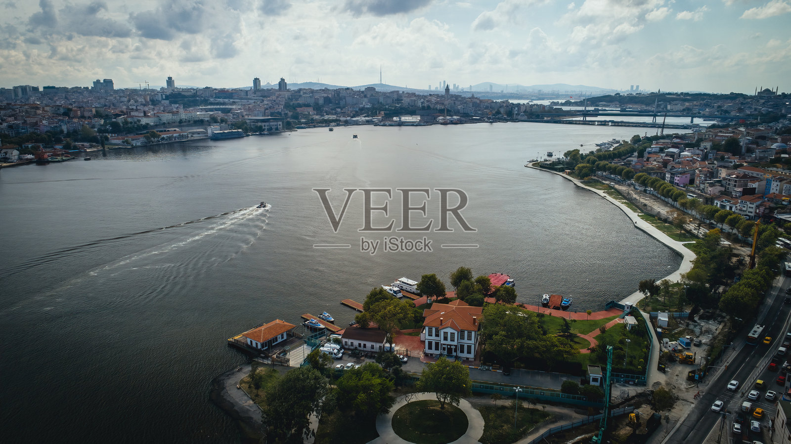 在伊斯坦布尔的一个多云的日子里，无人机拍摄了分隔两岸和大桥的海景。一艘帆船在海面上快速行驶。照片摄影图片