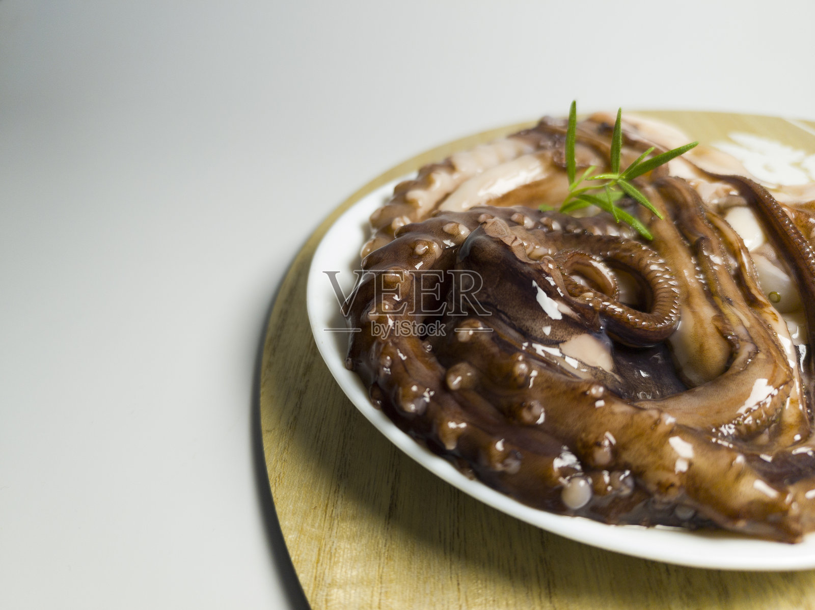 新鲜的章鱼放在白色的盘子里准备烹饪。白底海鲜照片摄影图片