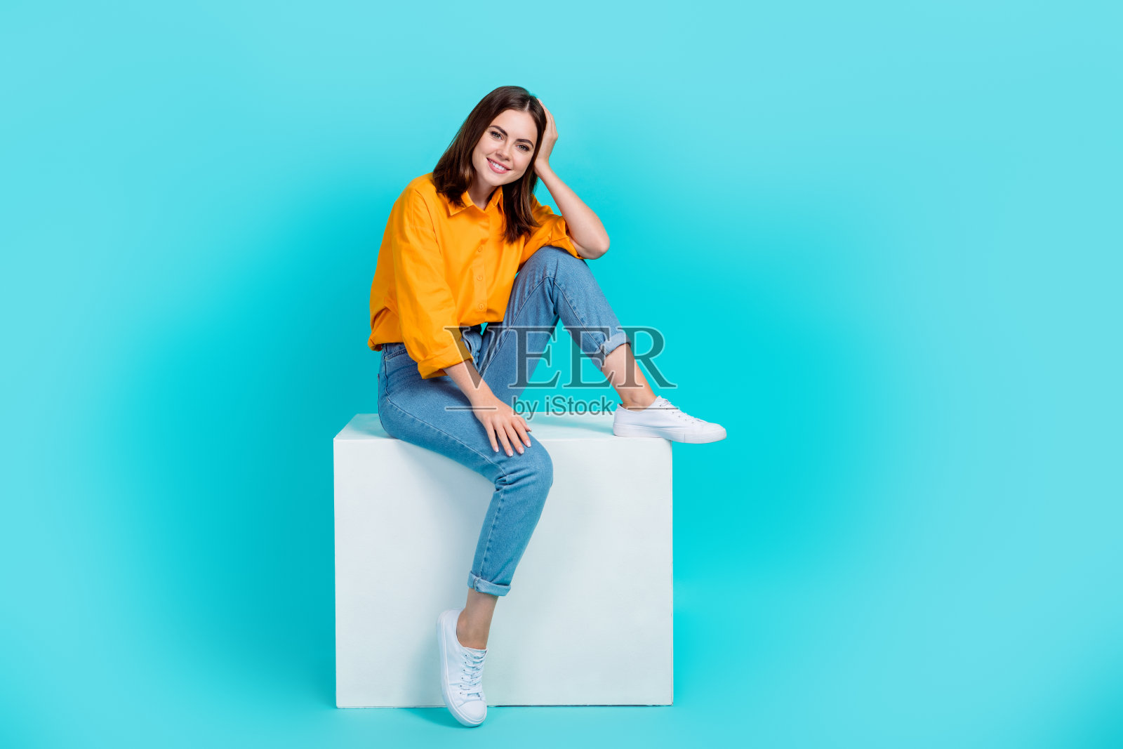 迷人梦幻女士的全身照片穿橙色衬衫坐在立方体孤立的绿松石色背景照片摄影图片