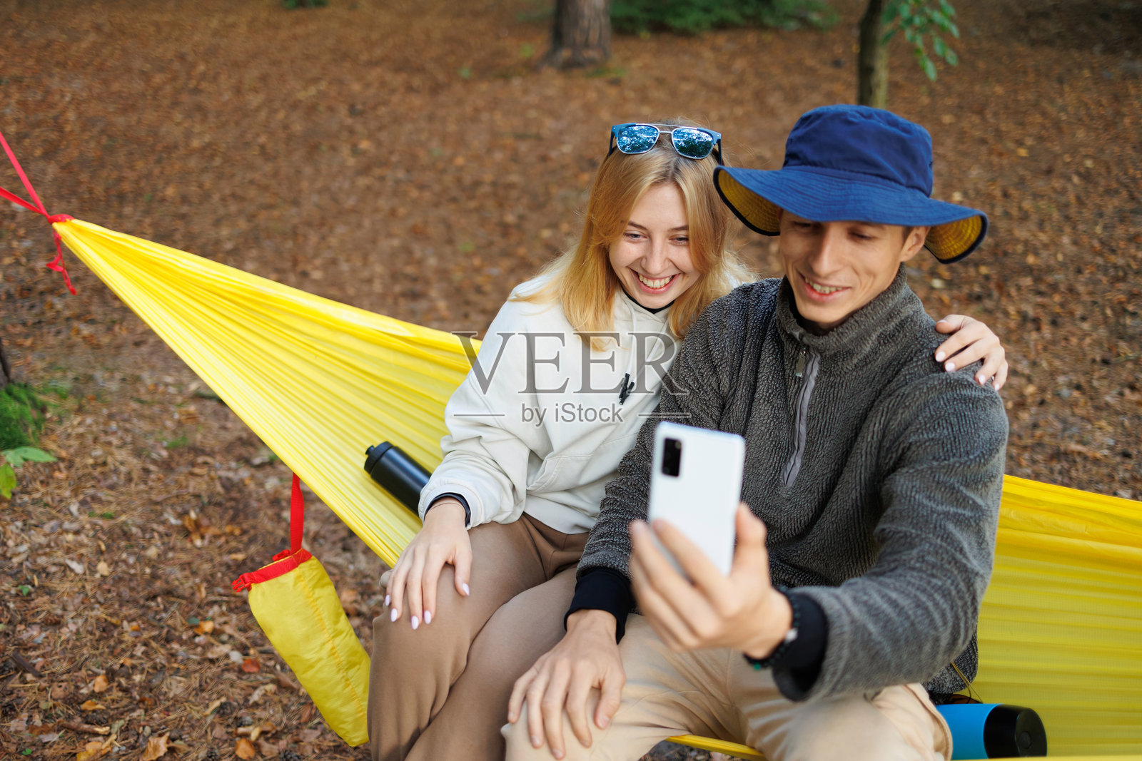 年轻夫妇在吊床上放松，一起视频聊天照片摄影图片