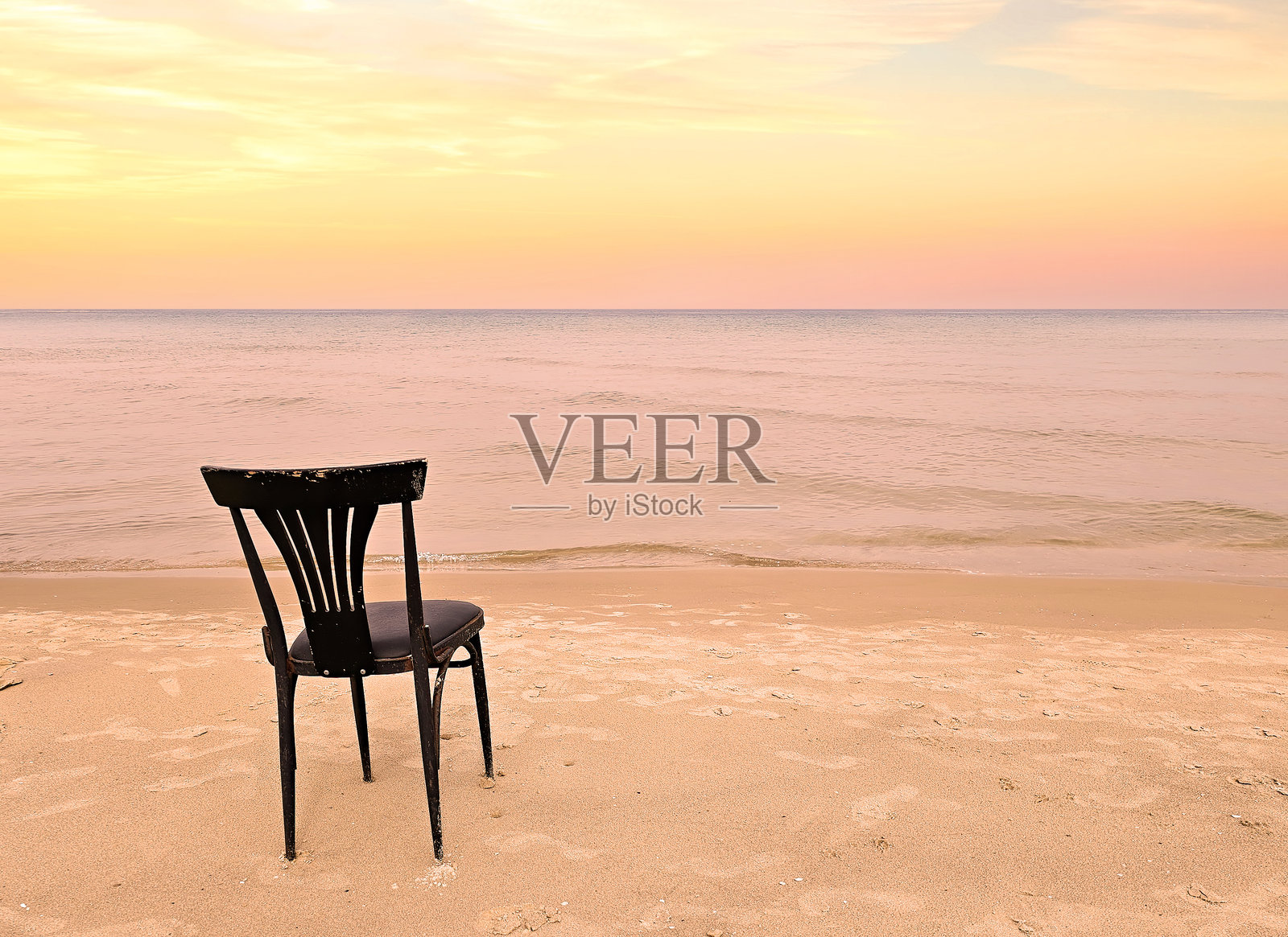 海边的清晨：空无一人的沙滩上，一把古老的黑色木椅，日出背景，地中海照片摄影图片