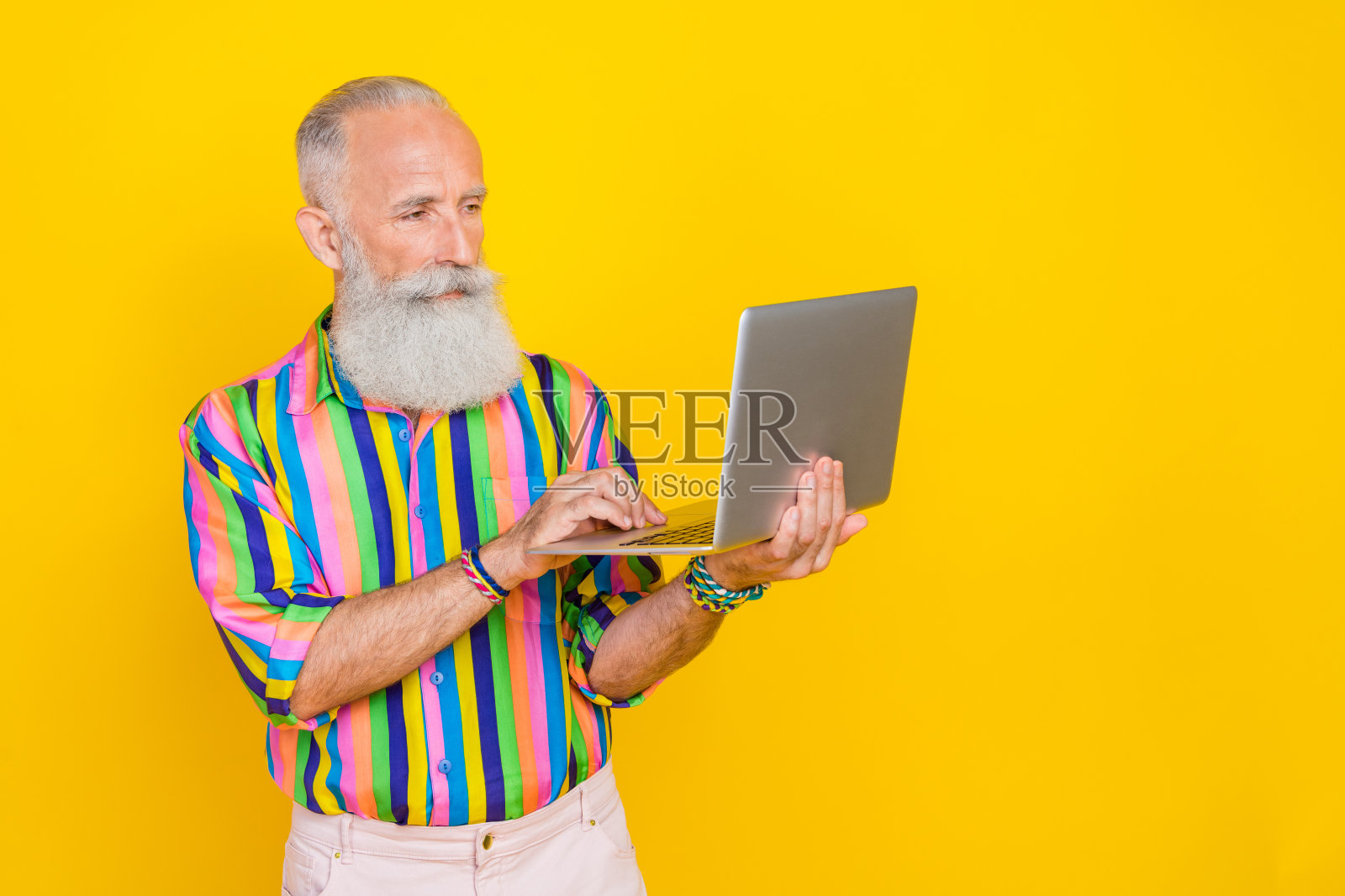智能平静老人的照片用无线上网本隔离在黄色背景上照片摄影图片