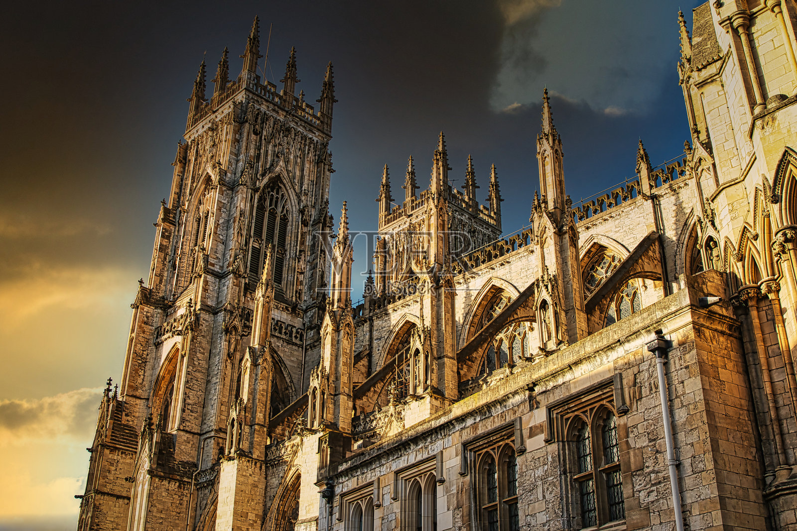 雄伟的哥特式大教堂在日落时分映衬着戏剧性的天空，展示了英国约克郡错综复杂的建筑和历史的宏伟。照片摄影图片