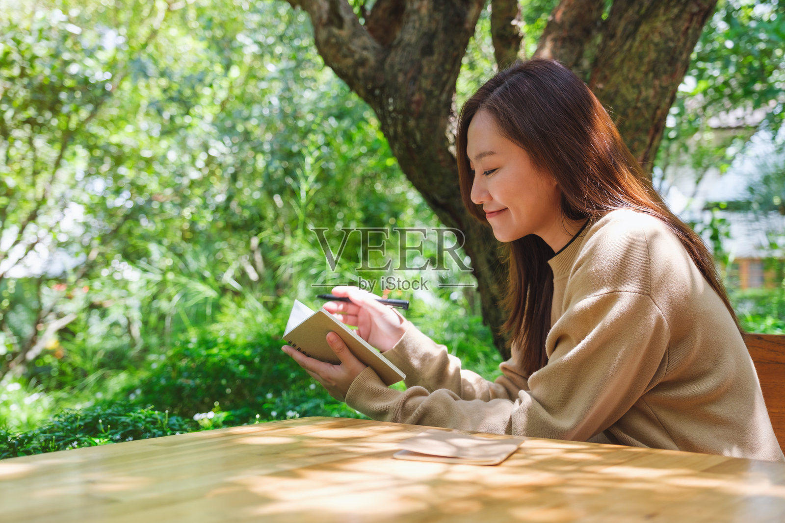一个女人在花园里在笔记本上写字的肖像照片摄影图片