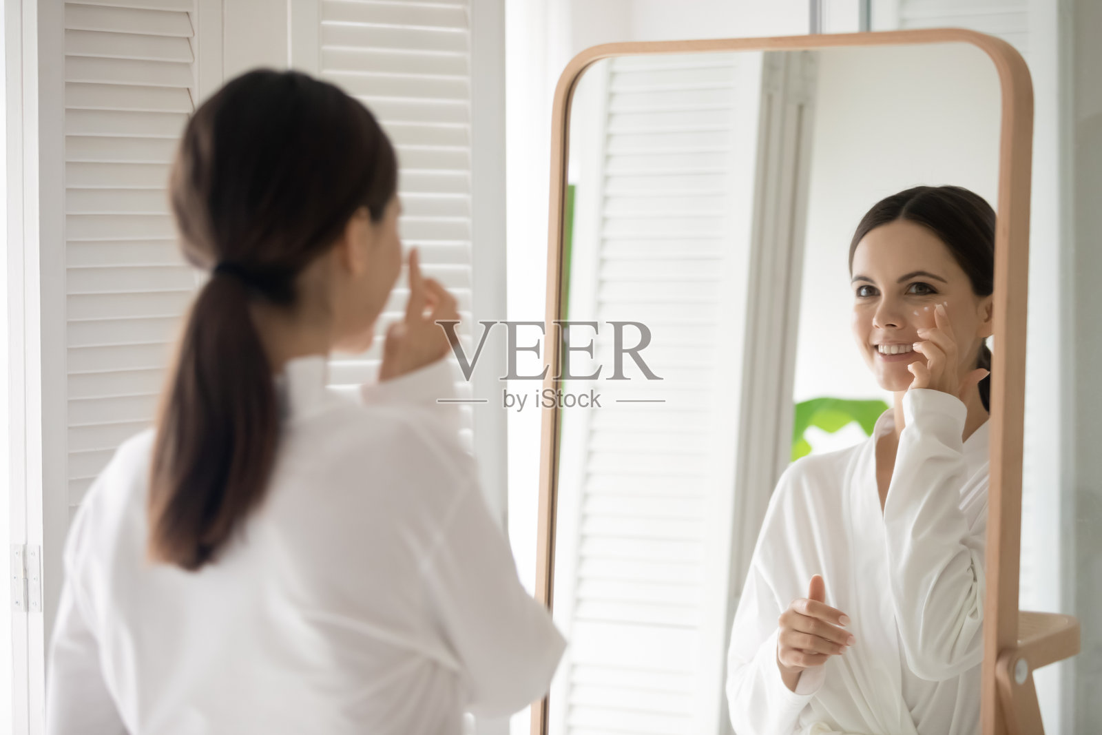 快乐的年轻女子在家做面部美容手术照片摄影图片