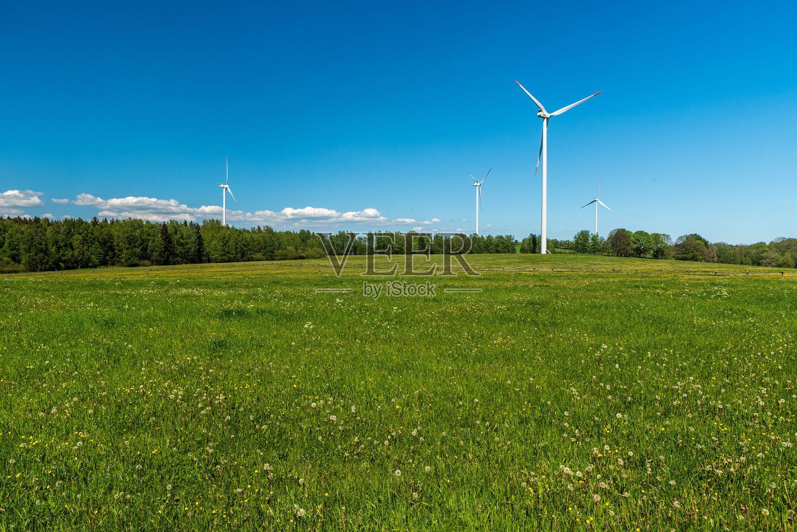 风力涡轮机在山上覆盖着草地和森林在春天的一天与蓝天-斯特拉兹山附近的城镇照片摄影图片
