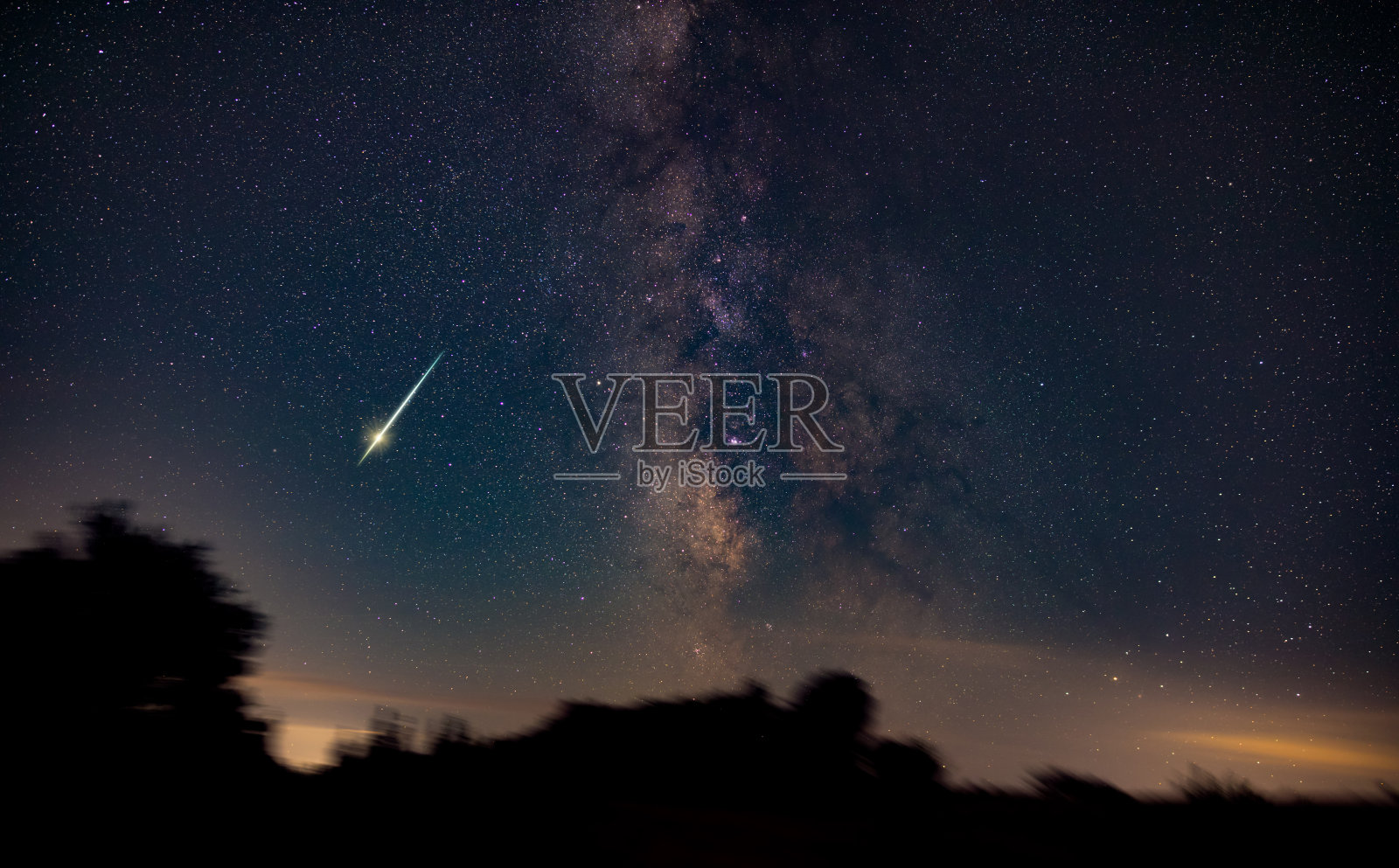 银河系的星星，流星雨的轨迹和乡村的剪影。照片摄影图片