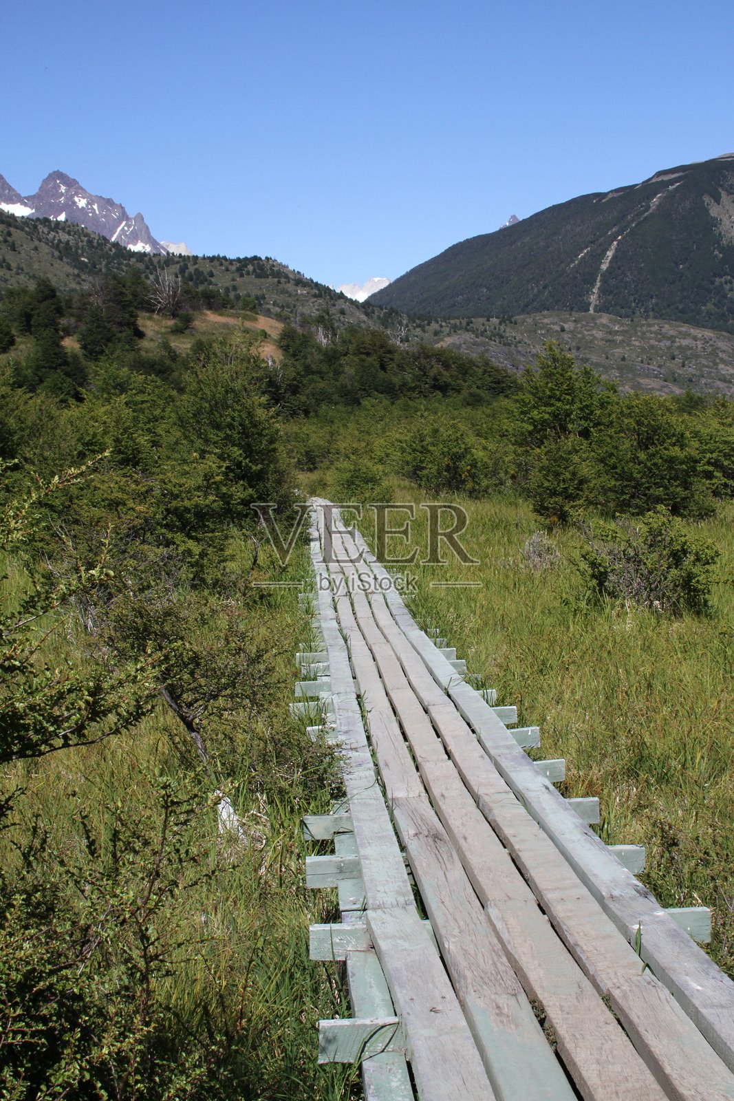 在草地上通往山脉的木板路的高角度视图照片摄影图片