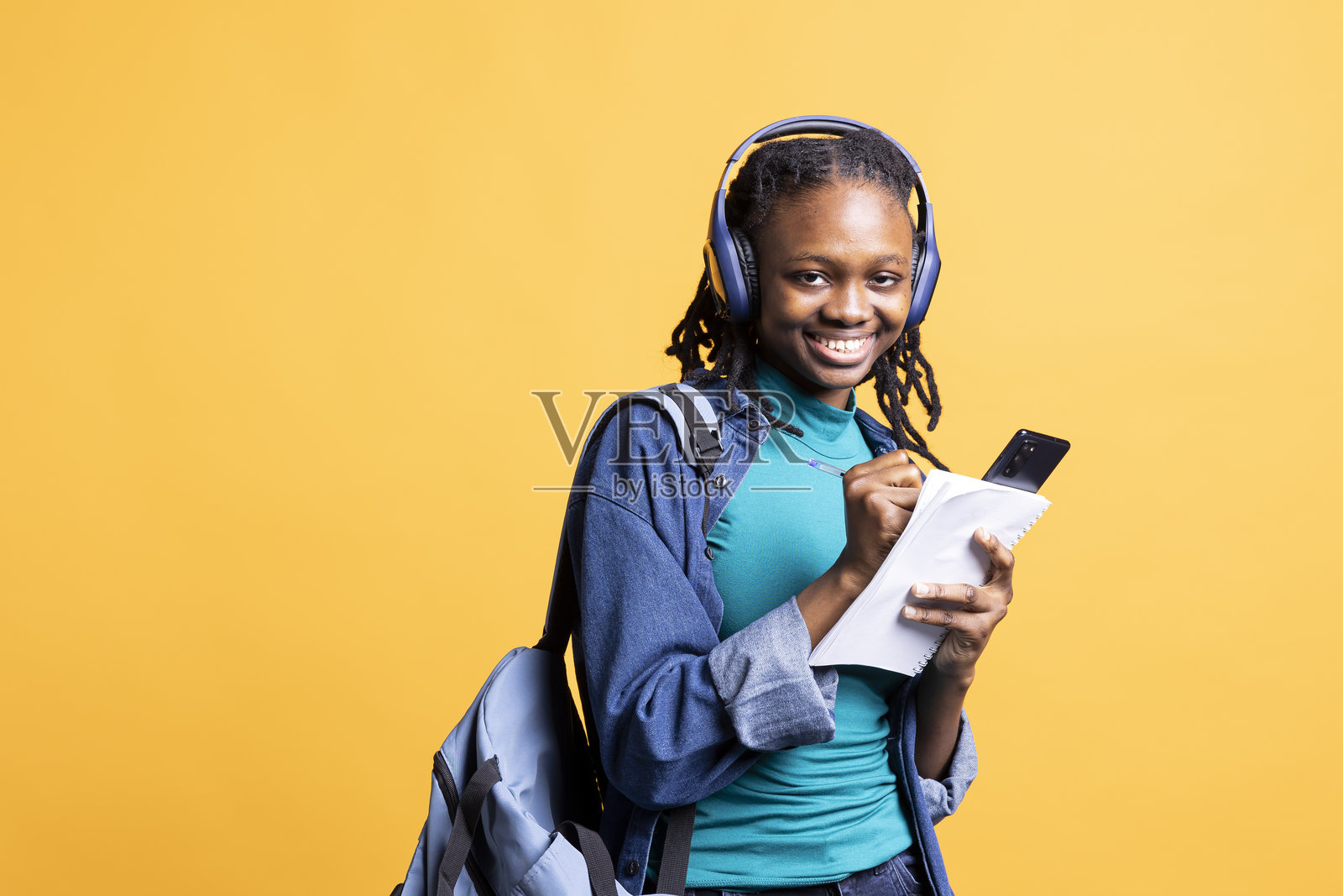 微笑的学生写作业，听音乐，工作室背景的肖像照片摄影图片