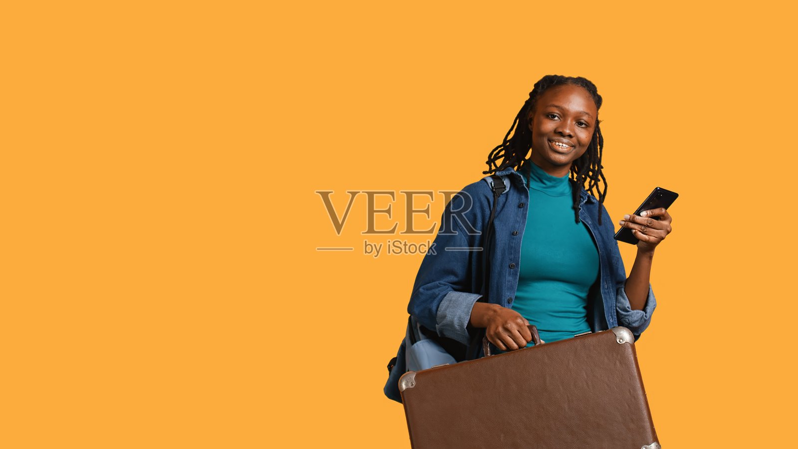 微笑的女孩带着行李箱去度假，看短信，工作室背景照片摄影图片