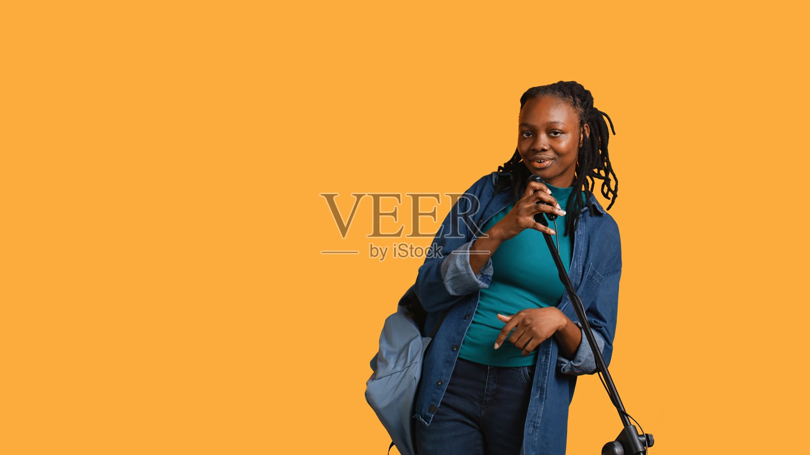 拿着麦克风又唱又跳的女人，演播室背景照片摄影图片